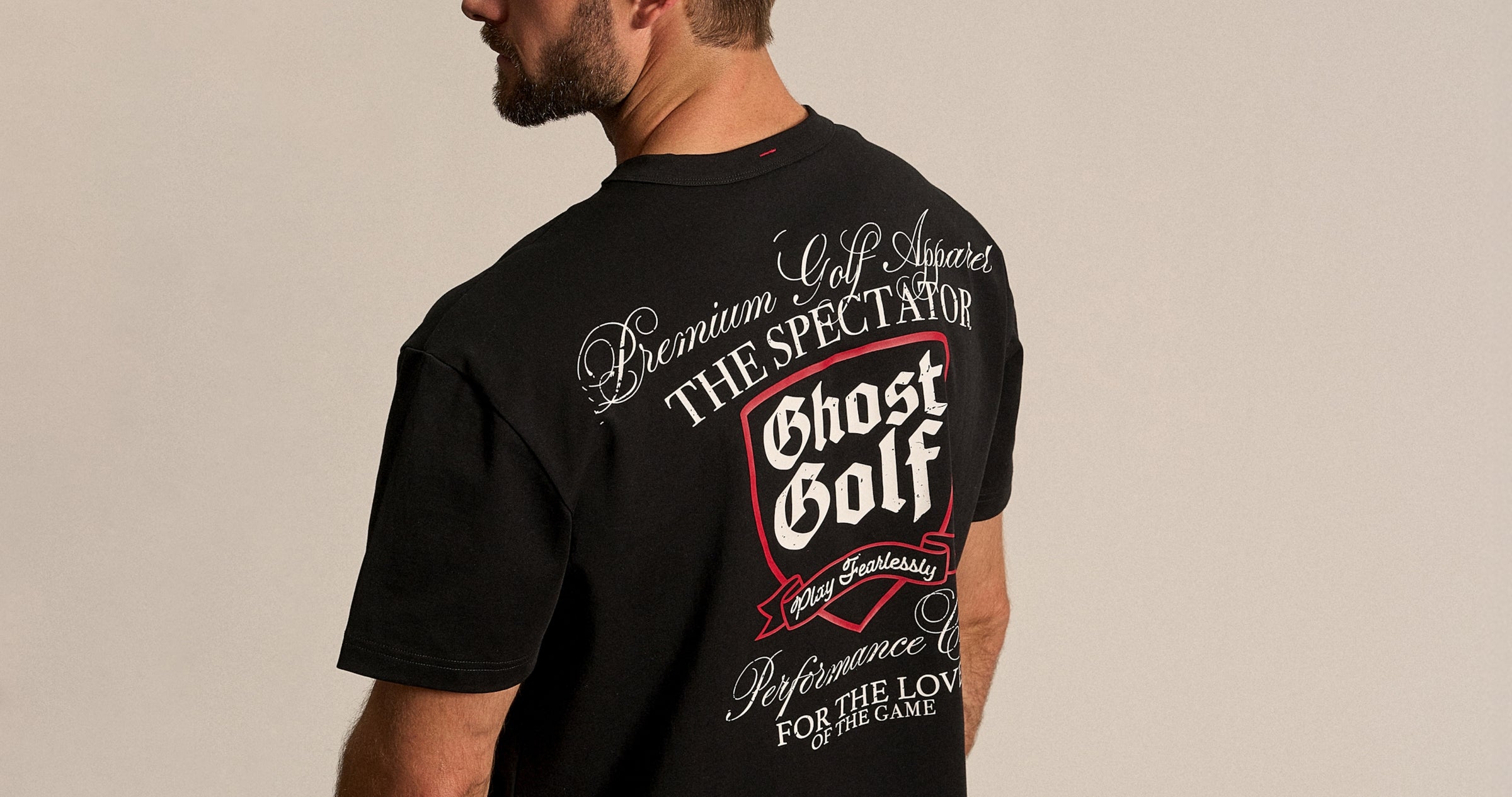 White Male in studio, back facing, wearing a black Ghost Golf graphic tee.